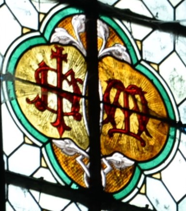 Vitrail aux monogrammes IHS et MADétail sur les monogrammesÉglise de Jouy-le-Châtel  - Repère 7IHS : IESUS HOMINUM SALVATOR [Jésus Sauveur des Hommes])(Translittération de IHΣ, premières lettres de Jésus en grec)MA : pour Marie